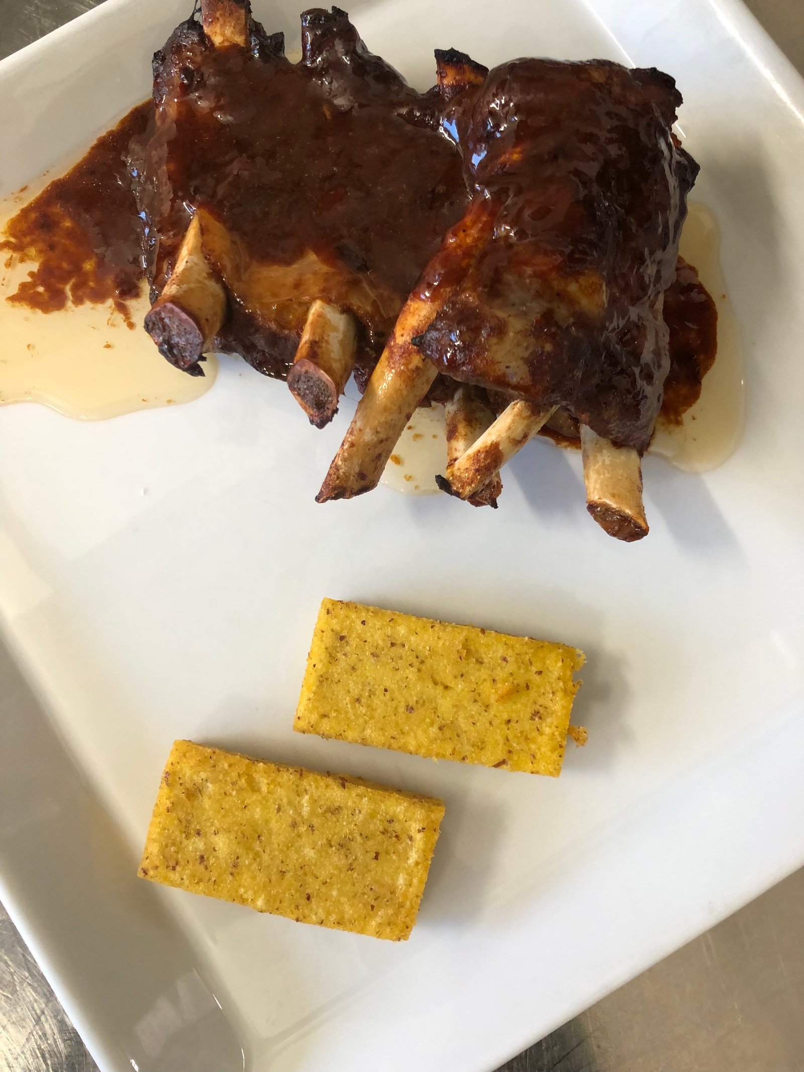 Costicine di maiale cotte a bassa temperatura in salsa BBQ con patate e crostone di polenta arrosto